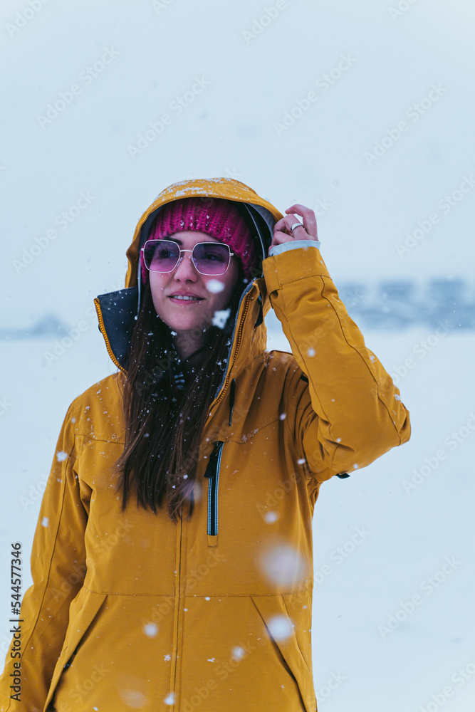 woman in the snow with yellow coat, hat and sunglasses