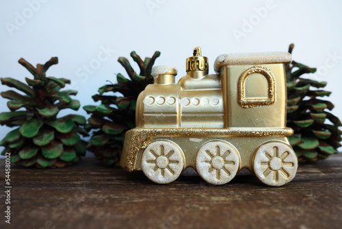 Golden children's toy train. Cones painted with green gouache like small Christmas trees. New Year or Christmas card. Icicles and snow on the train. Festive background. Christmas decorations