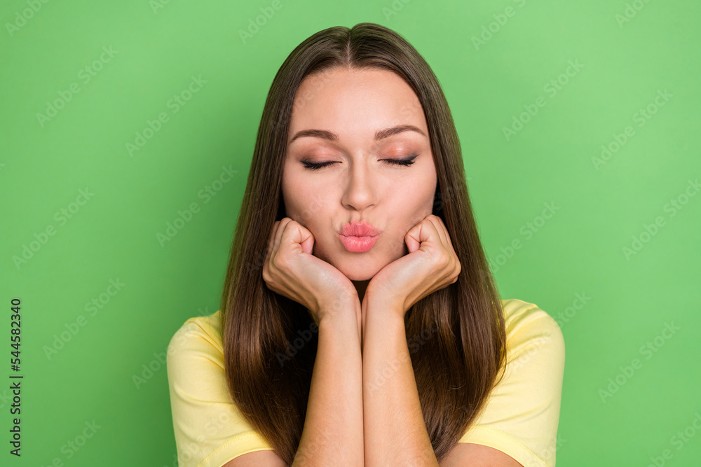 Portrait of cute nice stunning girl long hairdo yellow t-shirt arms under chin send kiss eyes closed isolated on green color background Portrait of cute nice stunning girl long hairdo yellow t-shirt arms under chin send kiss eyes closed isolated on green color background