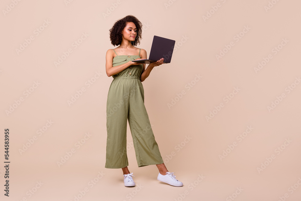 Full size photo of ceo brunette woman work laptop wear khaki overall isolated on beige color background Full size photo of ceo brunette woman work laptop wear khaki overall isolated on beige color background