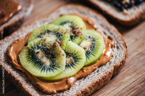 Foto Open sandwich from slice of wholegrain bread with peanut nut butter, kiwi slices