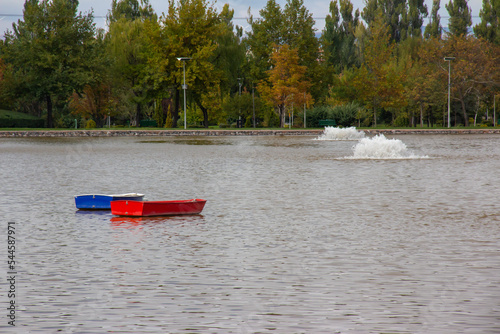 red and blue boat in the lake , background trees , autumn concept, red and blue caique