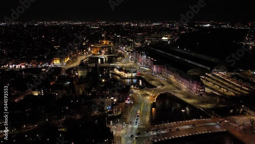 Amsterdam city center skyline by night aerial drone overhead view. Amsterdam Centraal, Ij, Oosterdok, Prins Hendrikkade, public transport, traffic at night. Bright lights urban photo