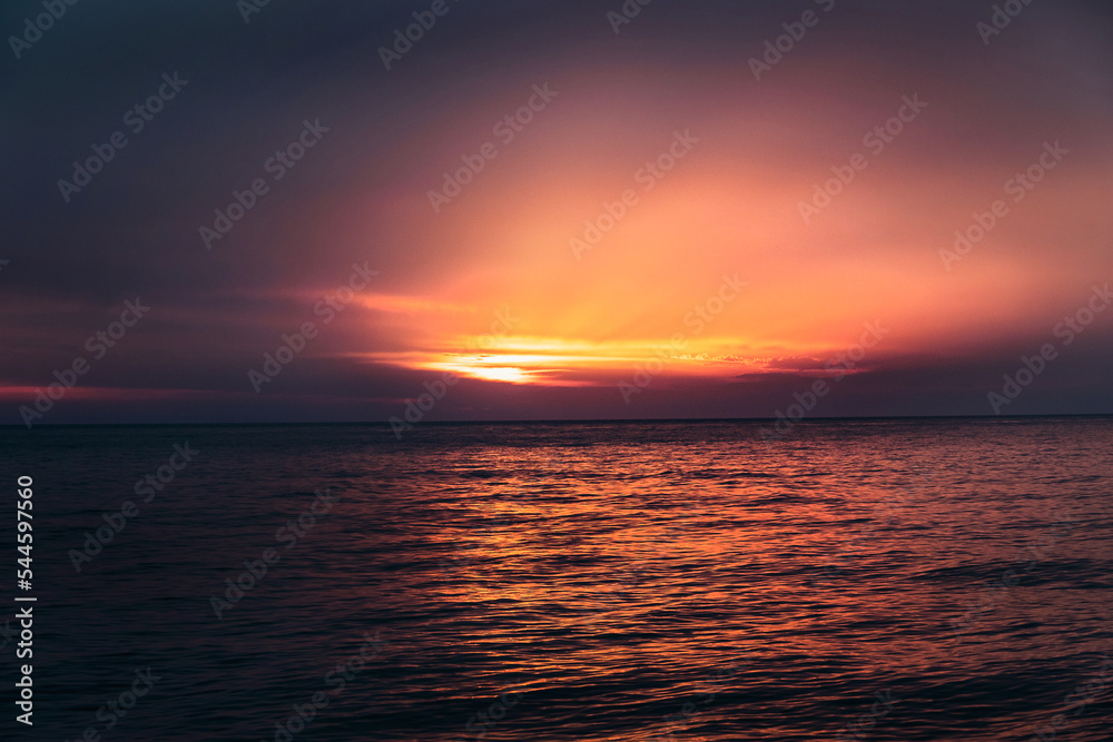 Sunset over the sea. A picturesque sunset over the ocean beach. Dramatic sunset sky over the sea. Sky and water in orange at sunset over the Black Sea. Sunset over the sea. A picturesque sunset over the ocean beach. Dramatic sunset sky over the sea. Sky and water in orange at sunset over the Black Sea.