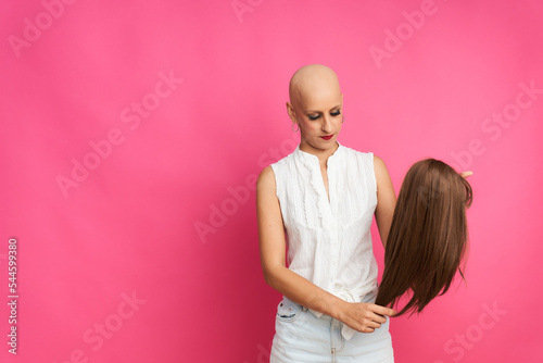 portrait of a woman suffering from breast cancer preparing the wig to cover her head without hair photo