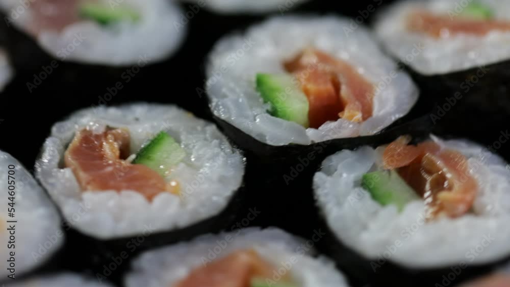 Close up sushi rolls rotating. Japanese food with avocado, salmon, tuna. Close up sushi rolls rotating. Japanese food with avocado, salmon, tuna.