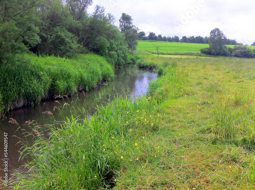 Stream of freshwater with bank along farming agricultural fields