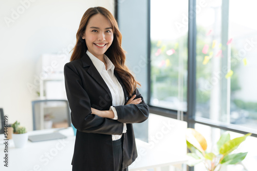 Young businesswoman standing with crossed arms smiling. © Naypong Studio