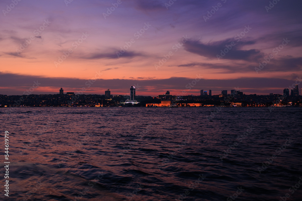 Orange sunset sky and sun over the sea. Silhouette of the city of Istanbul on the horizon.