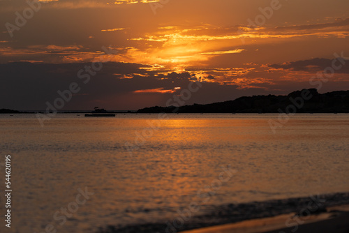 Orange sunset sky and sun over the sea. Water surface and outlines on the horizon. © Kozlik_mozlik