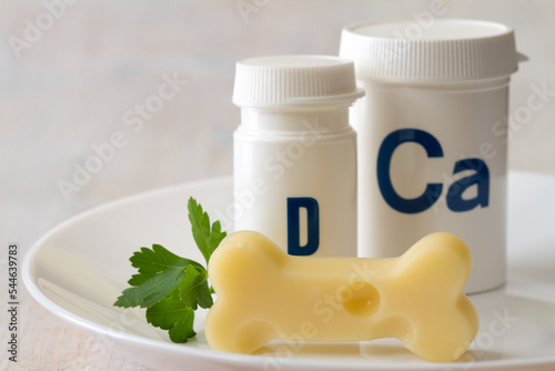 Foto Bone shaped cheese and dietary supplements with calcium and vitamin D on plate,