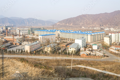 TUMEN, JILIN PROVINCE, CHINA - April 2008: contrast between modern Tumen buildings with blue roofs and old North Korean town Namyang in the background, Yanbian Korean Autonomous Prefecture photo