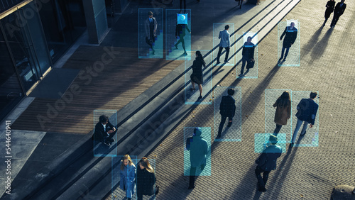 Elevated Security Camera Surveillance Footage of a Crowd of People Walking on Busy Urban City Streets. CCTV AI Facial Recognition Big Data Analysis Interface Scanning, Showing Personal Information. photo