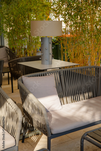 Obraz na płótnie Cosy place on the hotel terrace. Sofa and floor lamp. Hedge of greenery. Comfortable comfortable sofa in light shades. w salonie