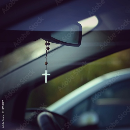 Kette mit christlichem Kreuz hängt als Glücksbringer am Rückspiegel im Auto