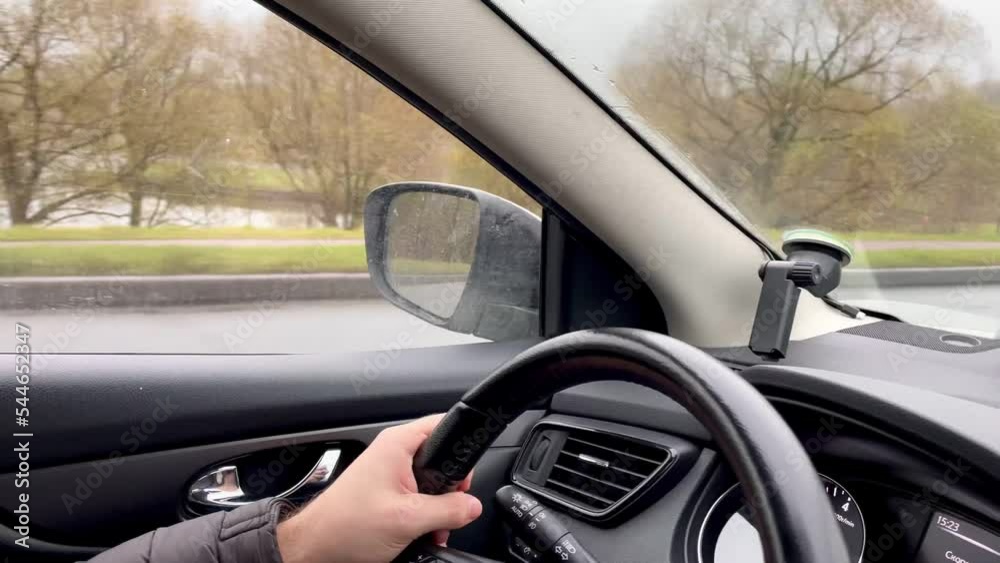 Hands on the steering wheel, a man driving a car on the road. The wipers on the glass are working. Autumn is outside the window. High quality 4k footage Hands on the steering wheel, a man driving a car on the road. The wipers on the glass are working. Autumn is outside the window. High quality 4k footage