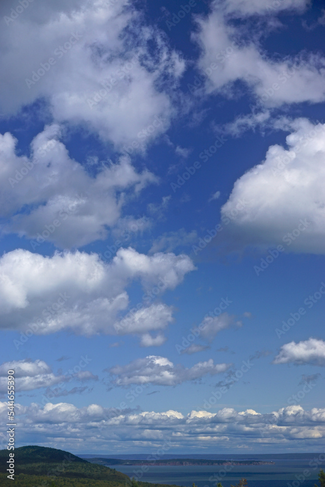 Fototapeta premium Fundy National Park, New Brunswick, Canada: Bright blue sky with fluffy white clouds over the Bay of Fundy at high tide.