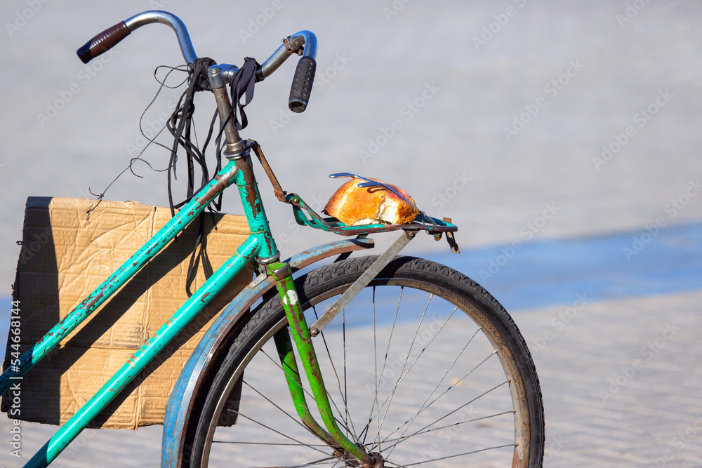 Obraz premium piece of bread on the trunk of an old bicycle. food and transport. poverty and survival in poor conditions