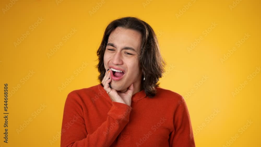 Portrait of Latino Hispanic gender fluid young hipster man 20s with tooth ache pain problem in mouth isolated on yellow background in studio Portrait of Latino Hispanic gender fluid young hipster man 20s with tooth ache pain problem in mouth isolated on yellow background in studio