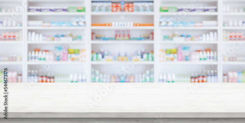 Fototapeta Empty white wood counter top with blur pharmacy drugstore shelves background