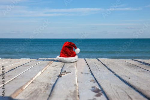 Weihnachtsmütze auf Holzterrasse mit Meer im Hintergrund
