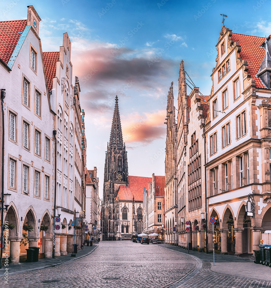 Scenic sunset view of Prinzipalmarkt square in Munster, Germany - without crowds of tourists at famous shopping street and tourist attraction. Saint Lamberti Tower at background.