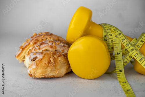 St. Martin's croissant with gym dumbbells, tape measure or measuring tape. Rogal marciński or świętomarciński. Traditional polish pastry with poppy-seed filling and nuts. Healthy diet choice concept. photo