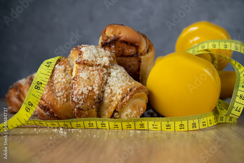 St. Martin's croissant with gym dumbbells, tape measure or measuring tape. Rogal marciński or świętomarciński. Traditional polish pastry with poppy-seed filling and nuts. Healthy diet choice concept. photo