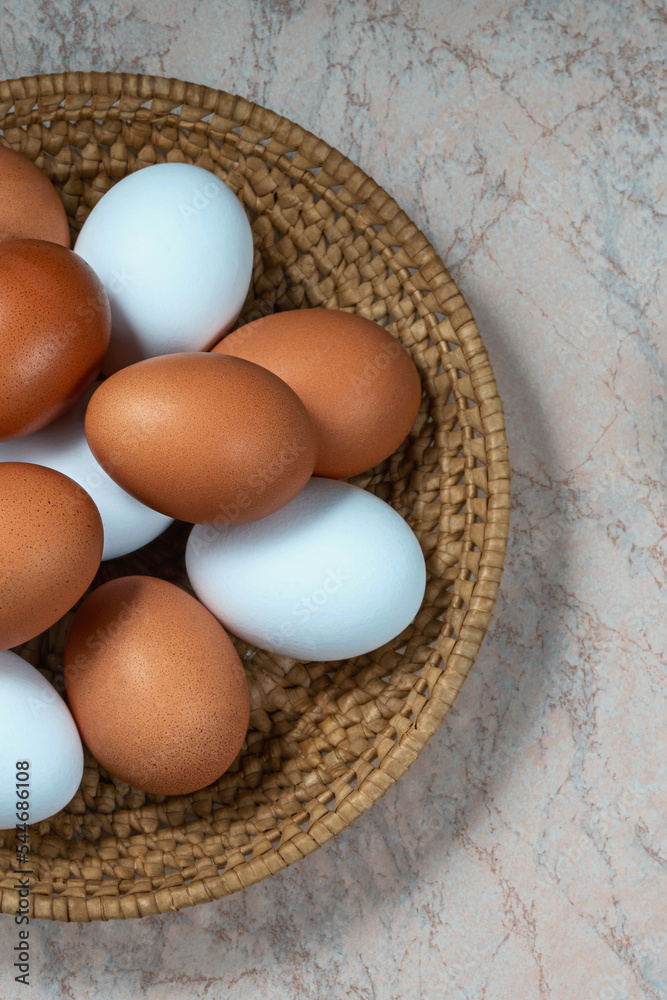 several fresh chicken eggs in a straw basket on a wooden background. Healthy eating concept. several fresh chicken eggs in a straw basket on a wooden background. Healthy eating concept.