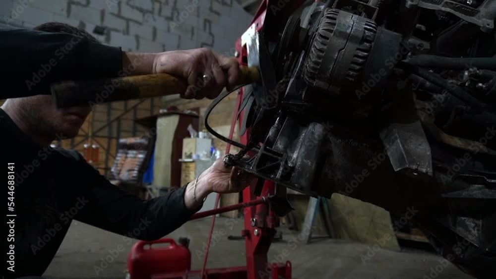 a mechanic disassembles an old dirty car engine on a red lift for repair and tuning a mechanic disassembles an old dirty car engine on a red lift for repair and tuning