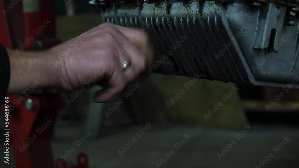 a mechanic disassembles an old dirty car engine on a red lift for repair and tuning a mechanic disassembles an old dirty car engine on a red lift for repair and tuning