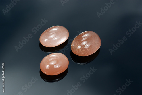 Billede på lærred Loose natural oval cabochon sunstone gemstones set light peach color with inclusions of hematite and copper in the mineral what gives a golden shimmer