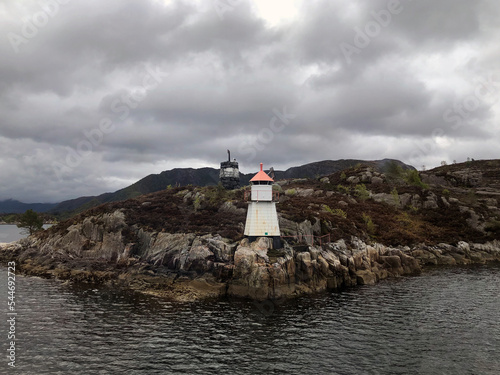 Norwegian seascape with tiny white lighthouse on rocks. Northern sea landscape, Norway, Scandinavia. Stunning Norwegian landscape with a lighthouse. Breathtaking Norway scenery. Norwegian nature