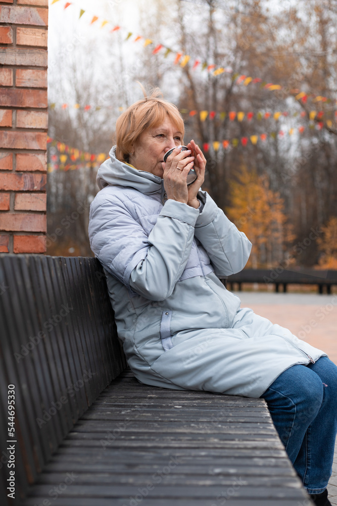 Mature woman is resting in the old city park. Drinking coffee Mature woman is resting in the old city park. Drinking coffee