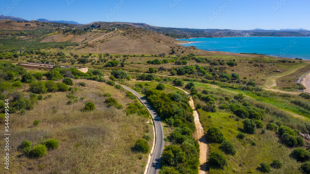 Panoramic view of a stretch of the Sicilian coast overlooking the Mediterranean Sea. Cultivated fields and hills that reach the sea. These beaches are located in Sicily, Italy.  Holiday concept. - obrazy, fototapety, plakaty 