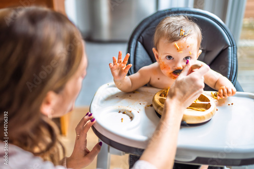 Little baby girl eating her dinner with her mother