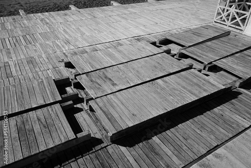 Detail of a wooden slat flooring, disassembled for the winter season, on the beach of a bathing establishment.	