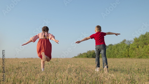Children boy, girl play in park, Friends run together raising their hands, dream is to fly to travel.Creative imagination of children, concept of active play in nature. Gun kids running. Happy family