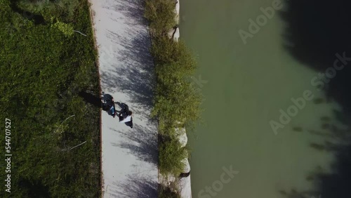 Electric scooters. Drone aerial sequence shot. Follow-up of a couple of boy and girl who ride their electric scooter along a bike lane on the banks of a city river. sustainable movement concept