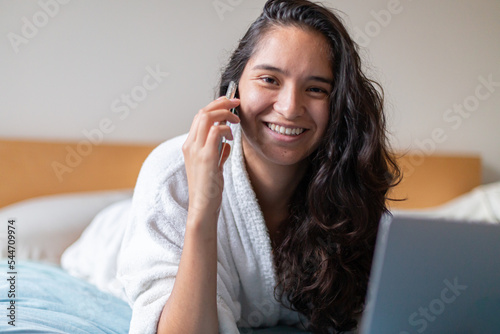 Happy woman speaking with cellphone in bedroom at home 
