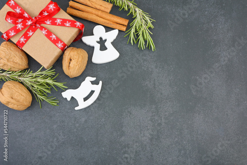 Christmas gift, cinnamon sticks, walnuts, rosemary and Christmas decoration on dark background © Polina