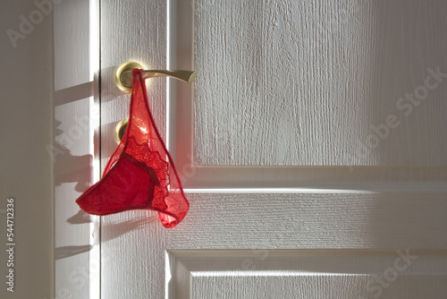 Red lace panties on the handle of the white door (Valentines Day background) 