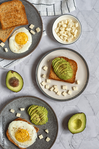 Avocado toast. Healthy breakfast: toast bread with fried eggs, avocado and feta cheese on a gray marble table. Healthy food. Healthy lifestyle. Top view. Flat lay.   photo