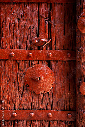 Puerta roja antiquísima de madera con remaches de hierro