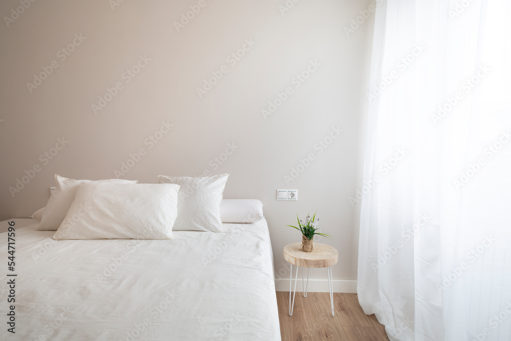 Fototapeta premium Bedroom with large white bed, natural wood floor, white curtain, small table