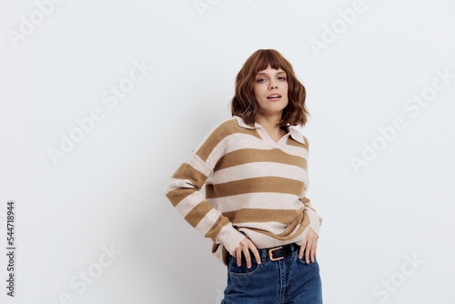  sweet woman stands in a stylish striped sweater and blue jeans with her hands near her pockets and smiles pleasantly. Horizontal photo with an empty space for inserting an advertising layout