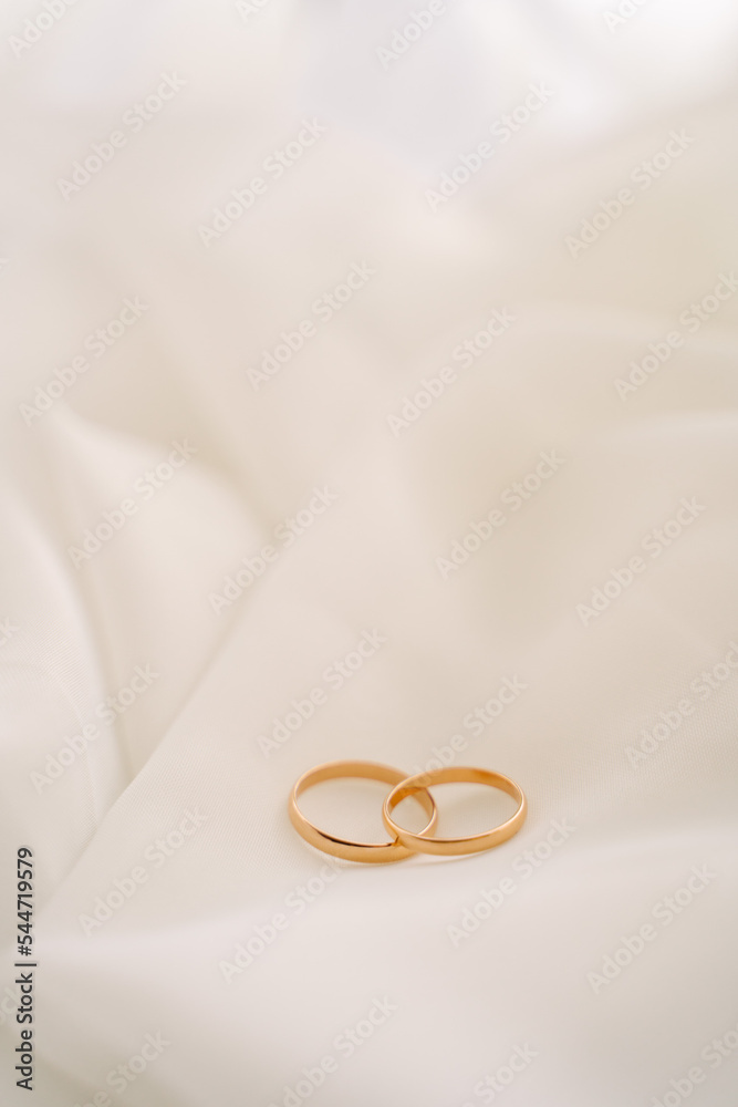 wedding rings on a white translucent chintz fabric, wedding gold rings lie on a white veil or tulle, free space for text wedding rings on a white translucent chintz fabric, wedding gold rings lie on a white veil or tulle, free space for text