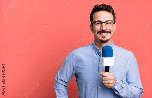 adult man smiling happily with a hand on hip and confident with a microphone. presenter or journalist concept