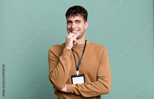 adult man smiling with a happy, confident expression with hand on chin with an acccess identity card photo