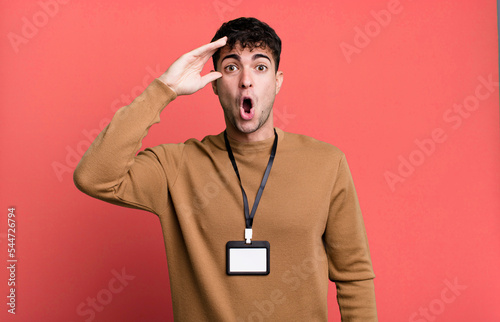 adult man looking happy, astonished and surprised with an acccess identity card photo